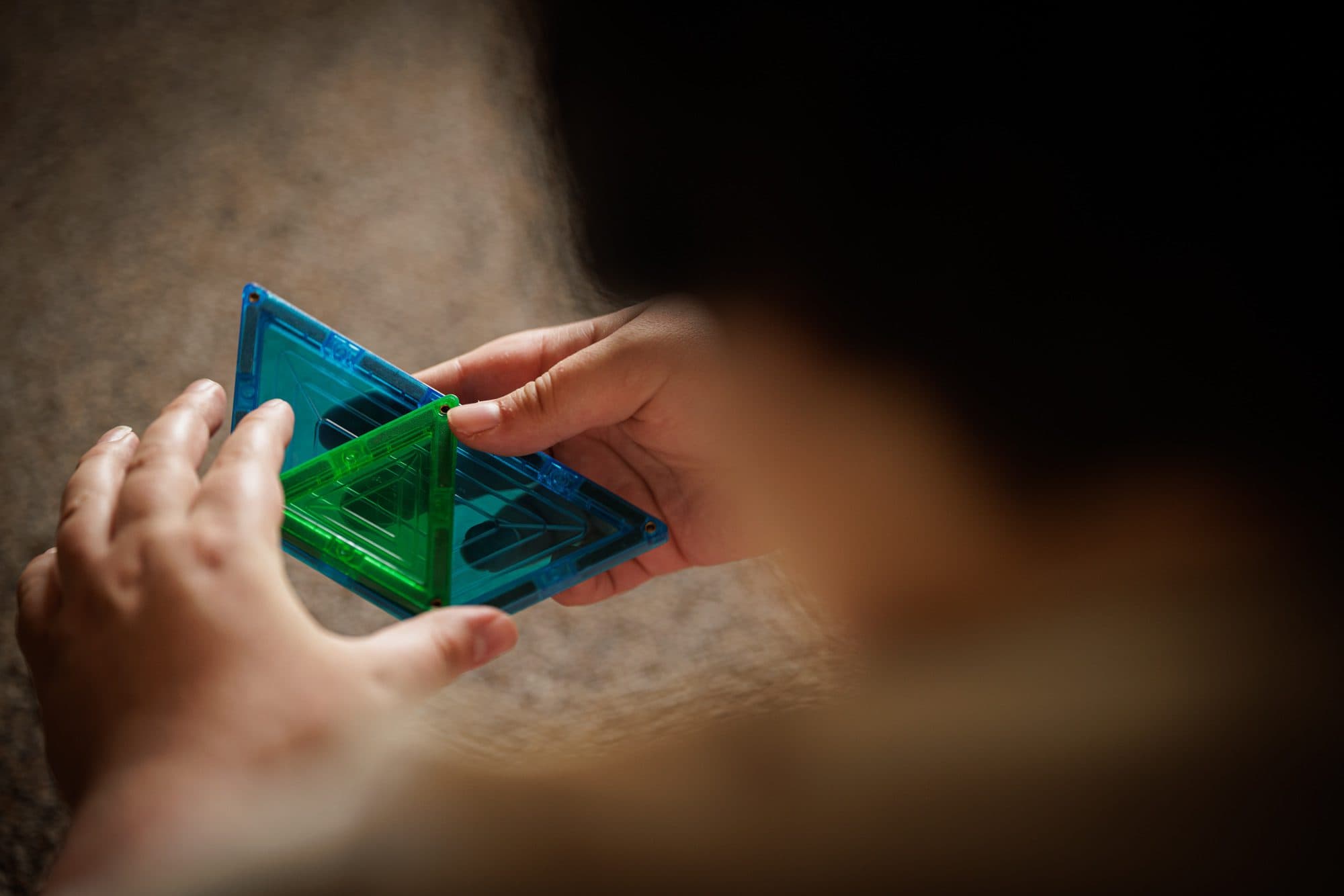 Student connecting magnetic tiles