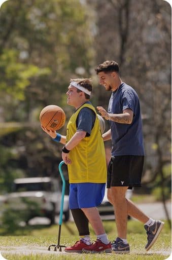 Student and staff member playing basketball outdoors