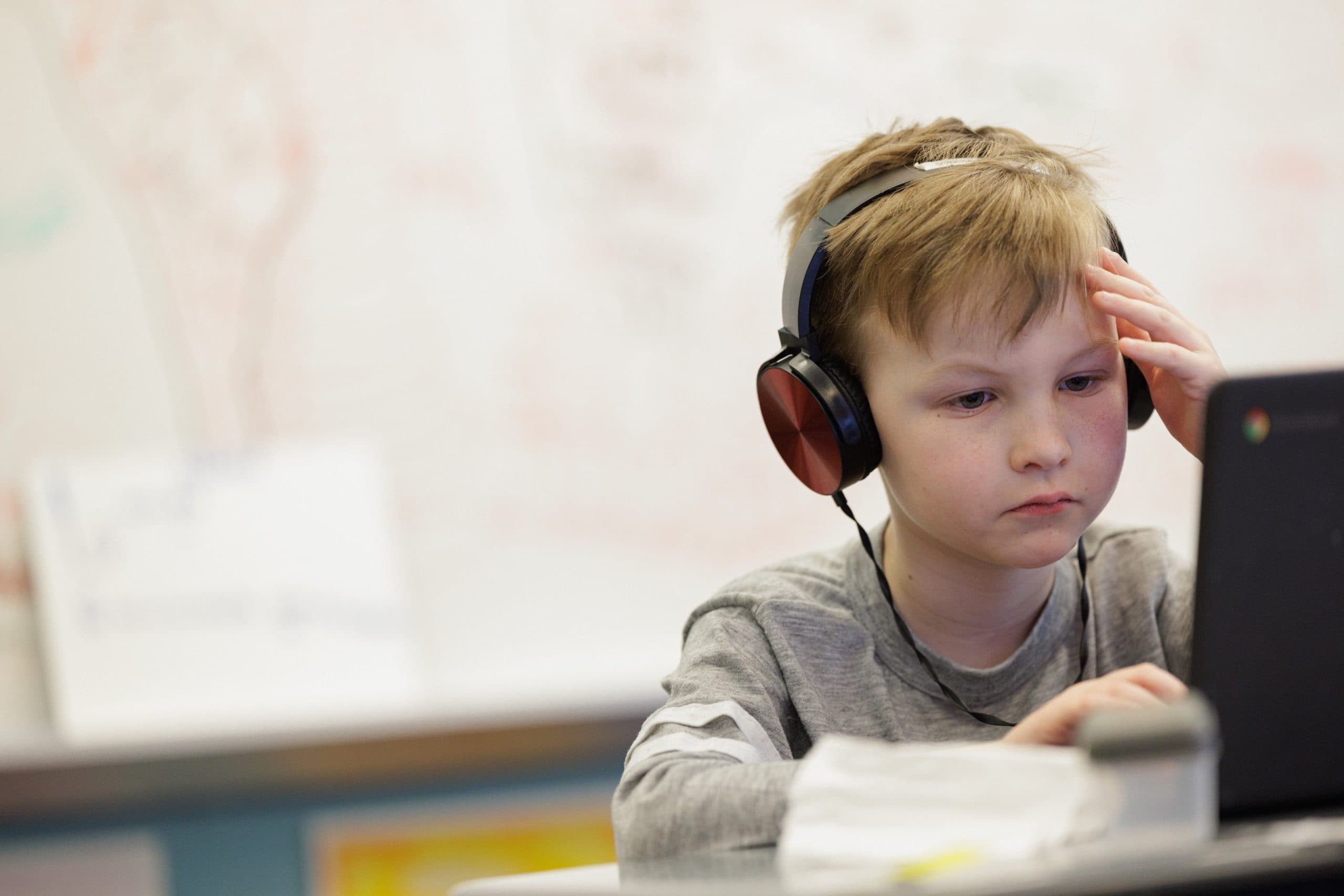 Student wearing headphones on a laptop
