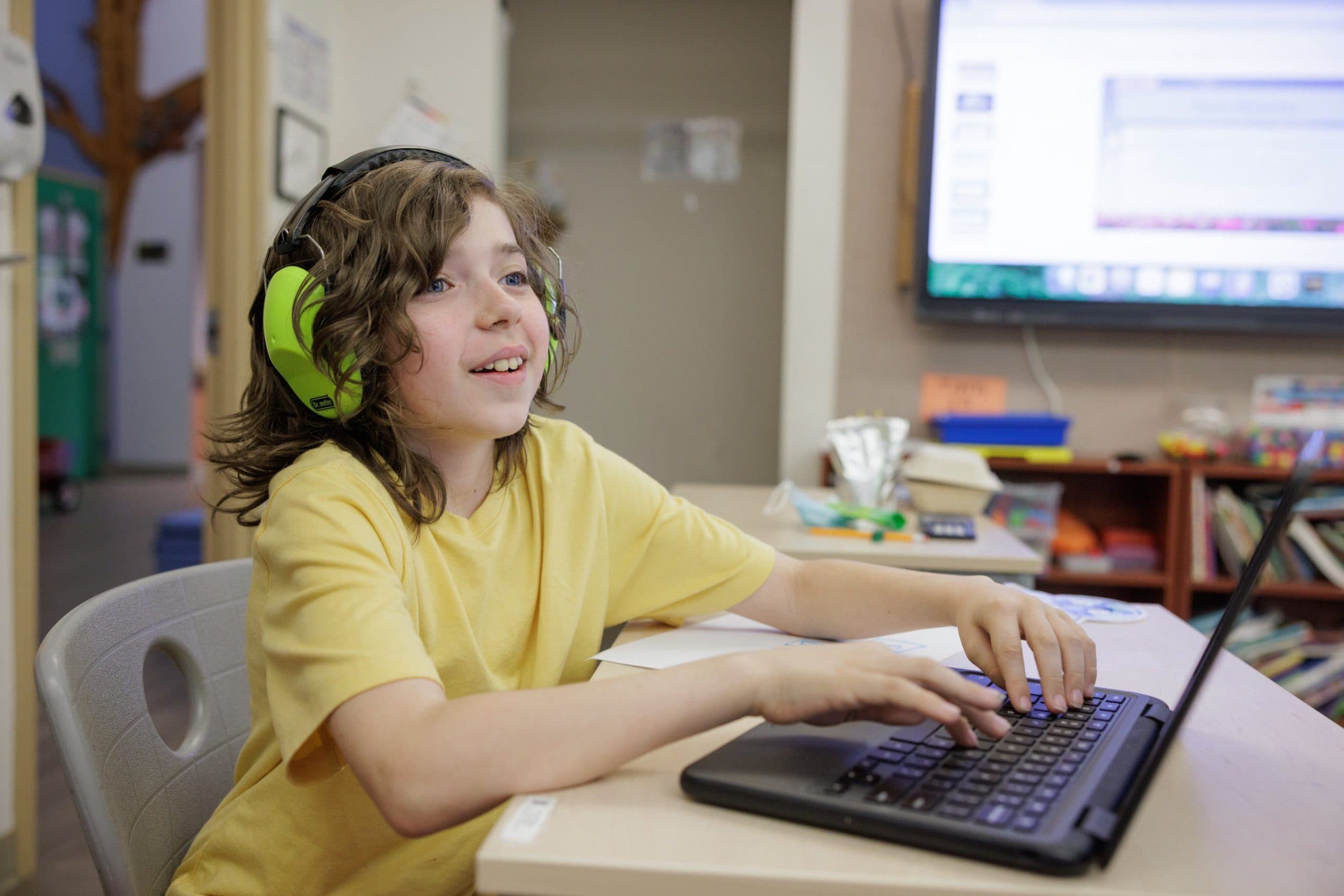 Student wearing noise-reducing ear protection while using a laptop