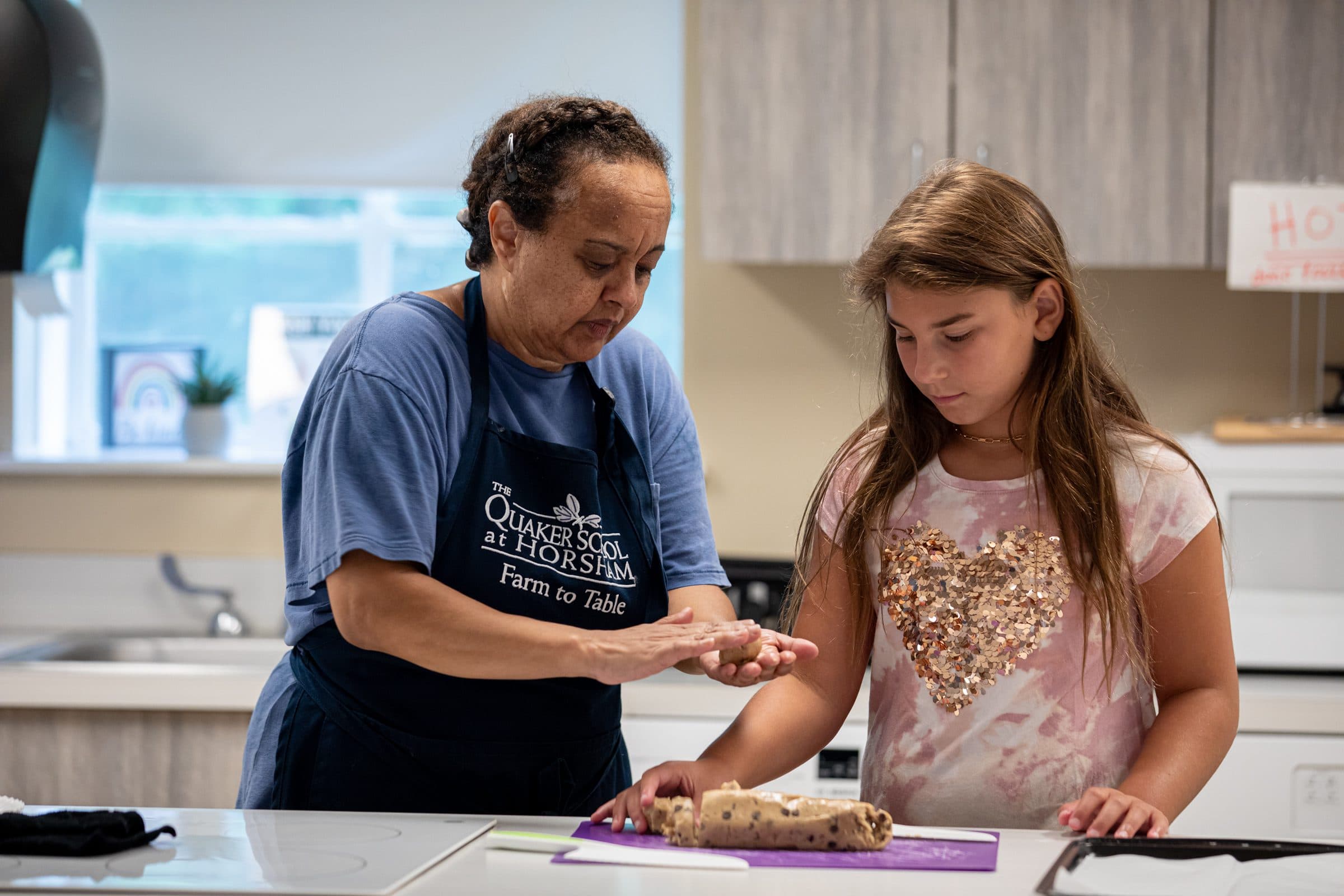 Staff member and student cooking together