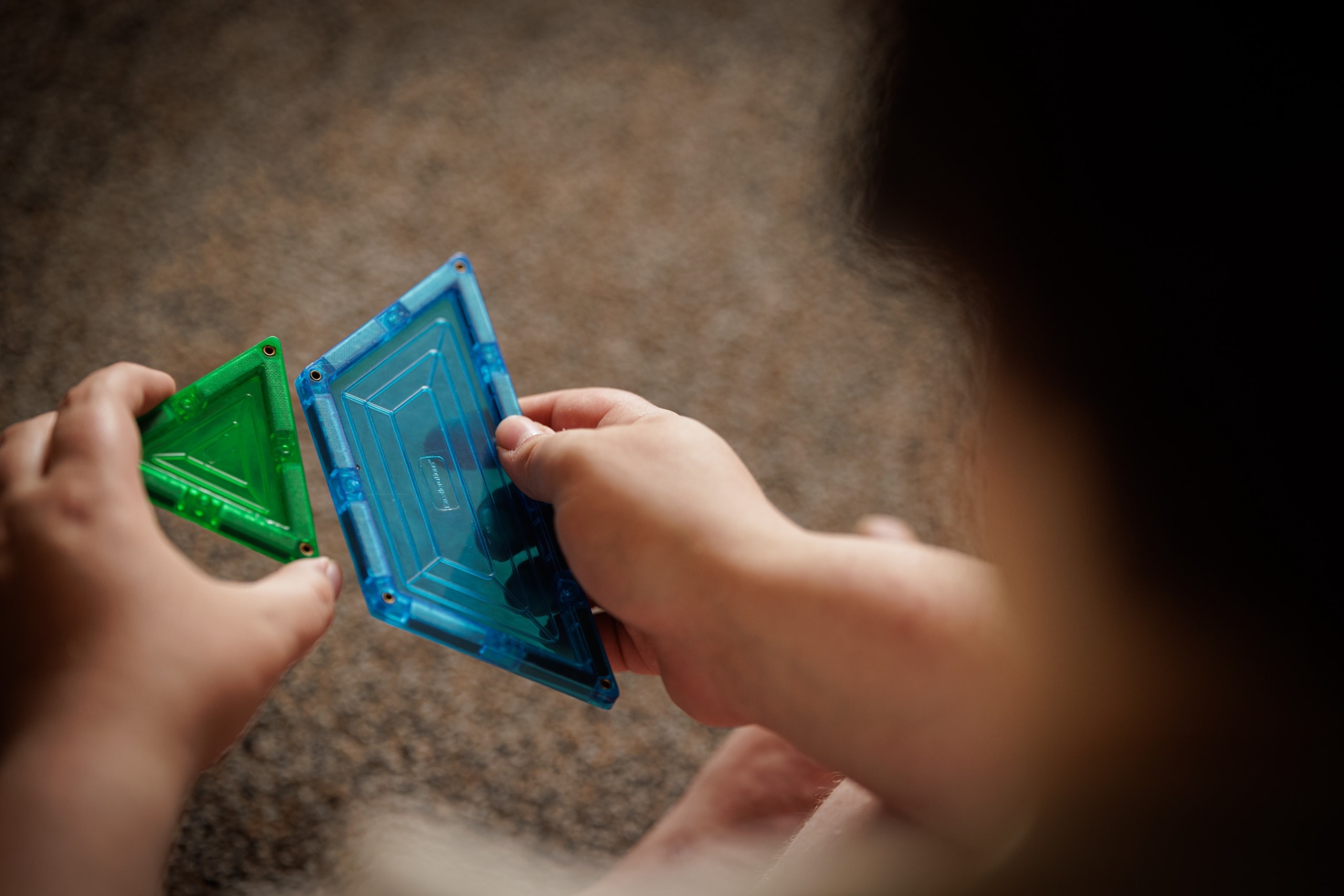 Student connecting magnetic tiles