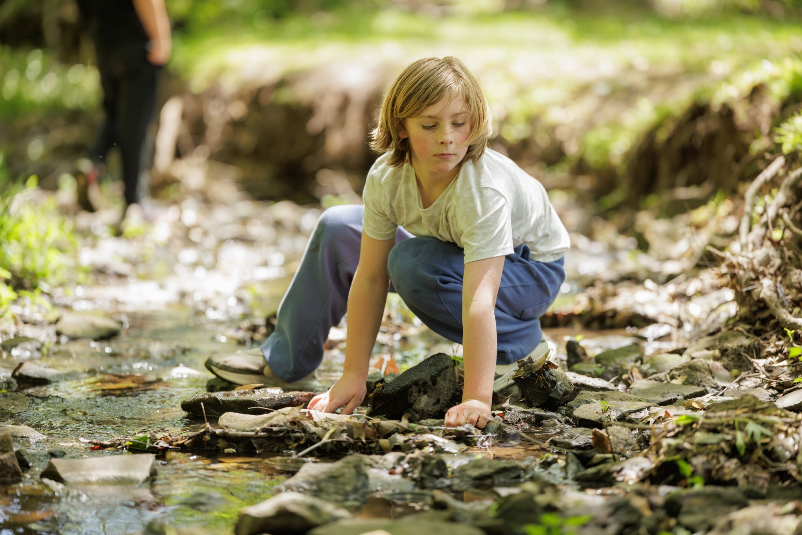 Student examining rocks in a stream