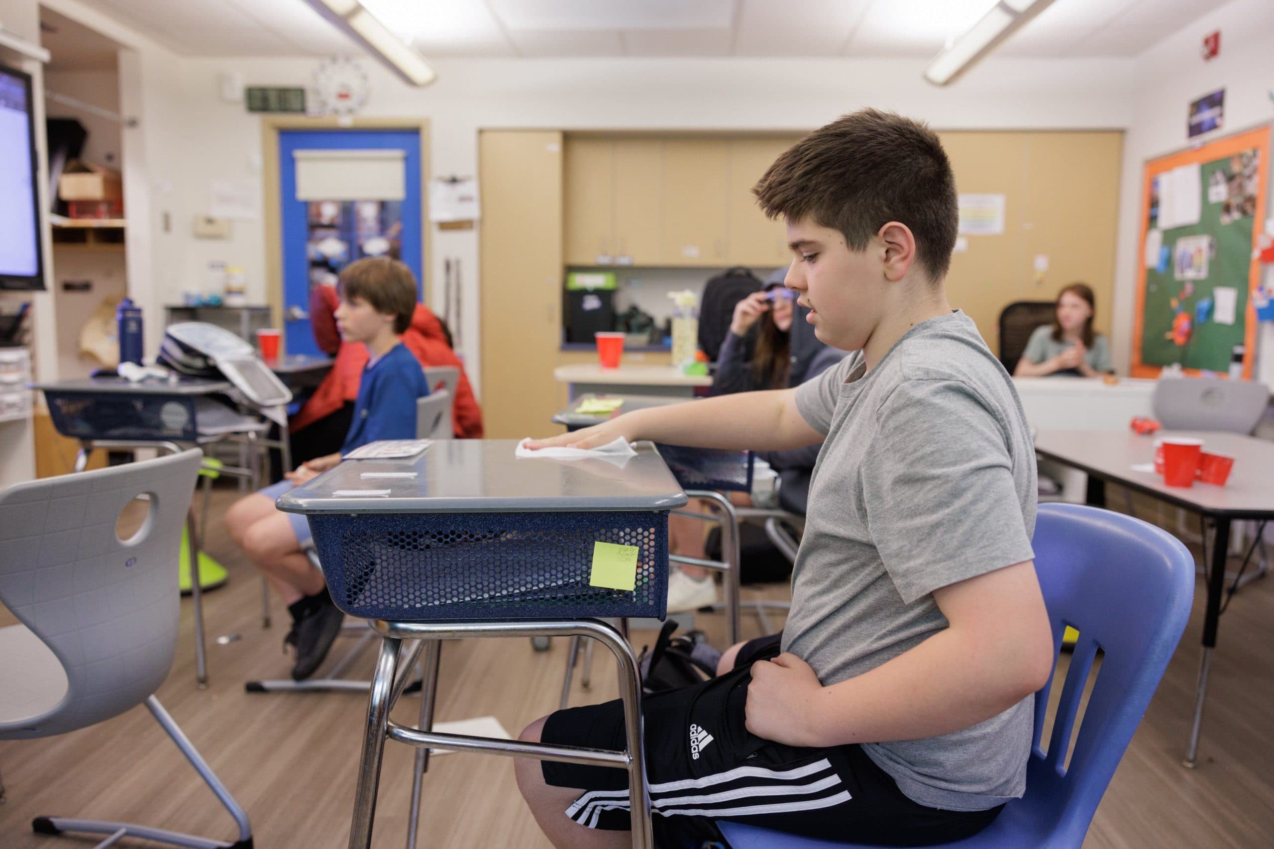 Student wiping a desk