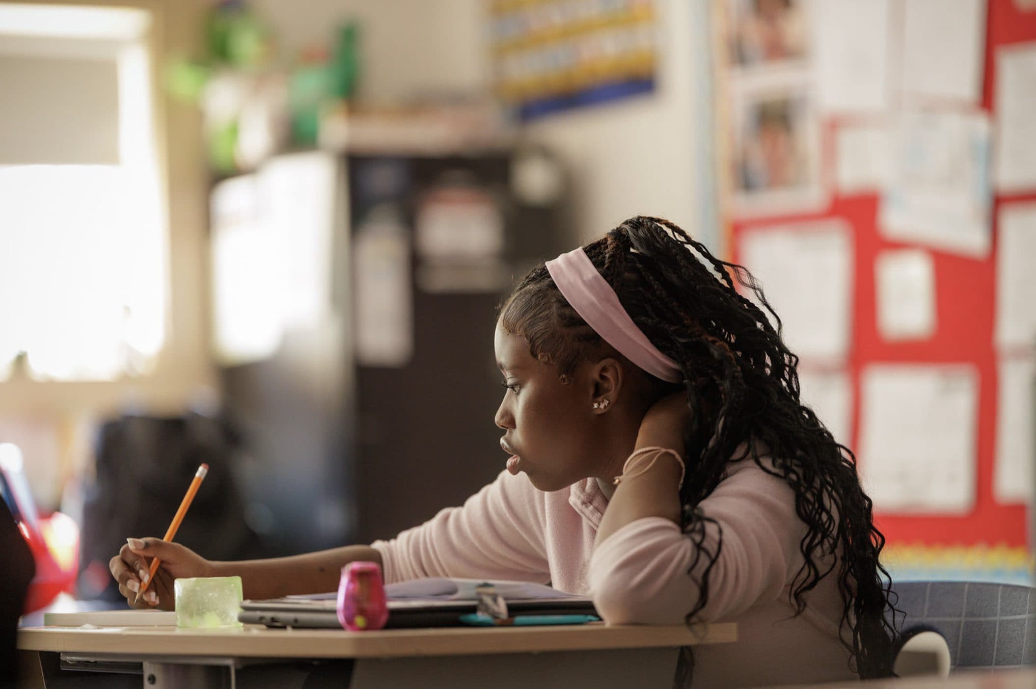 Student focused on writing at a classroom desk
