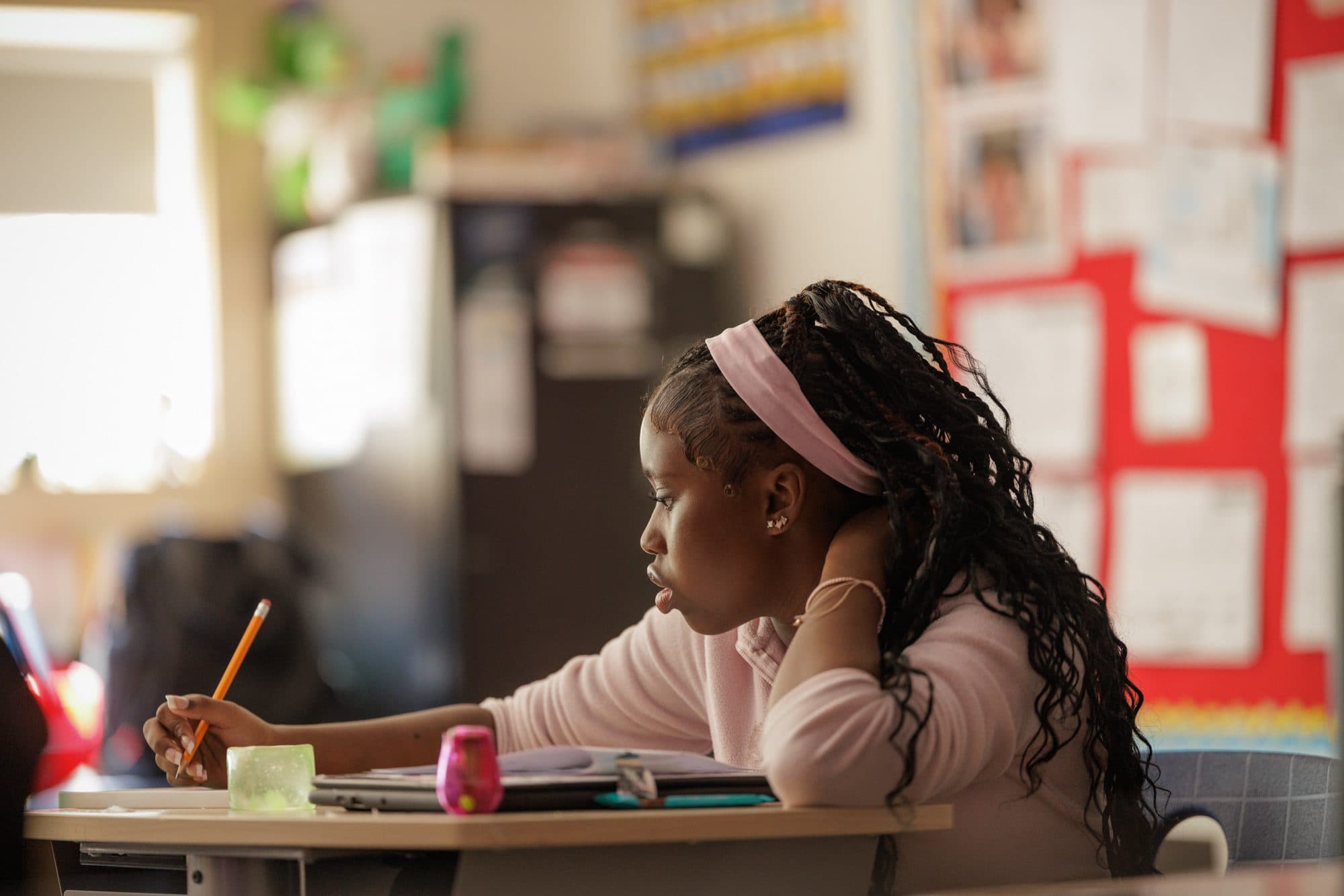 Student writing at a classroom desk