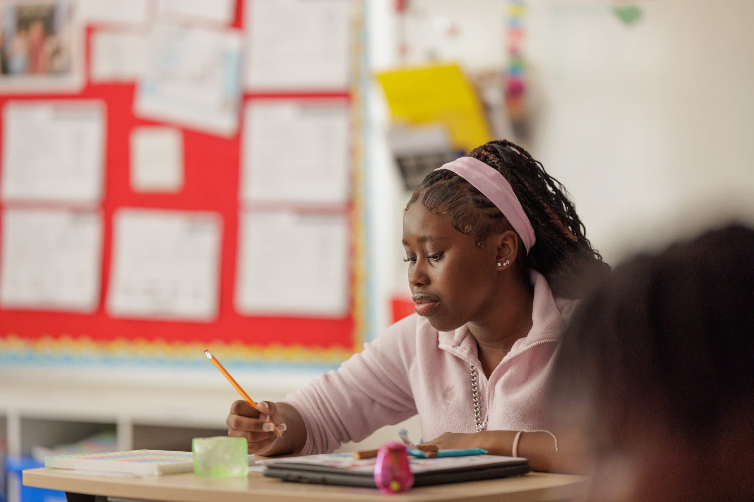 Student writing at a classroom desk