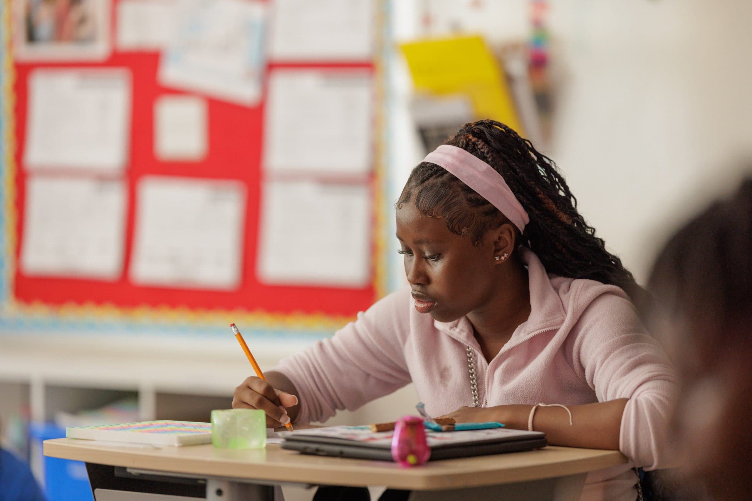 Student writing at a classroom desk