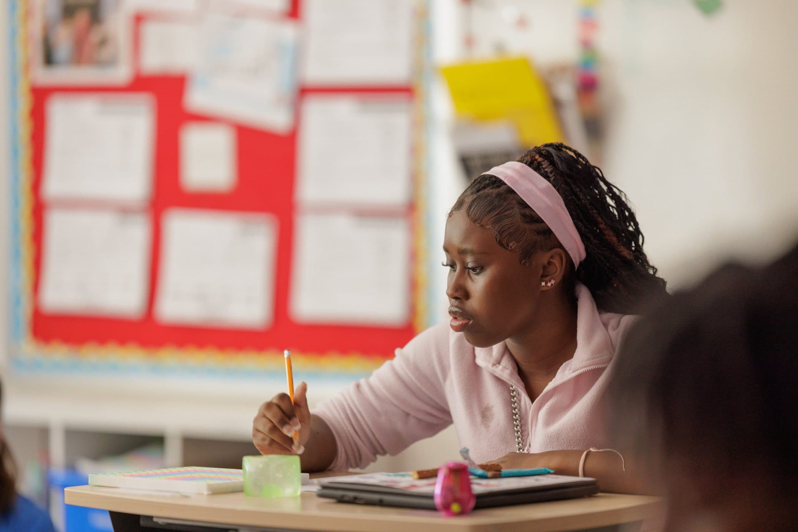 Student writing at a classroom desk