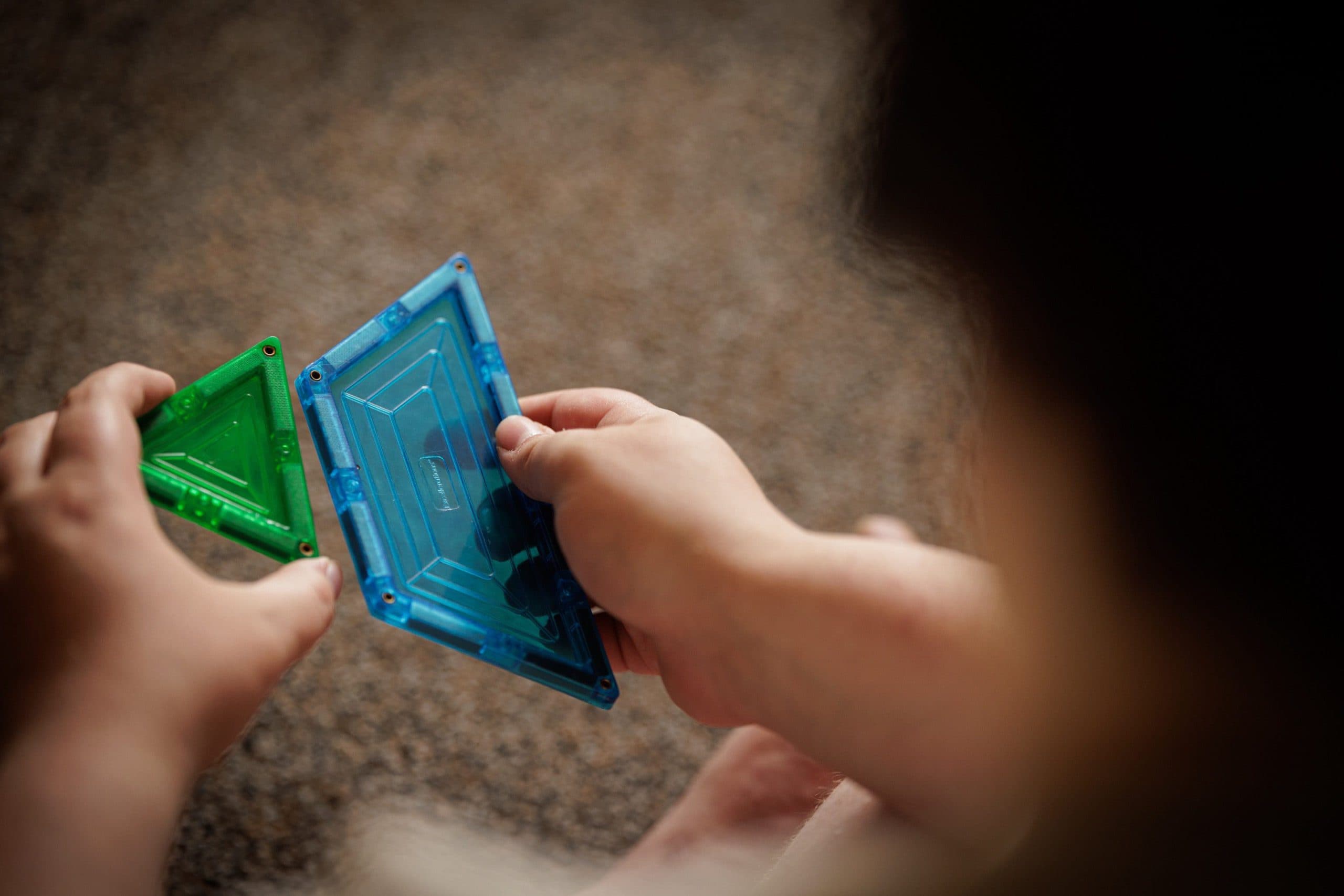 Student connecting magnetic tiles