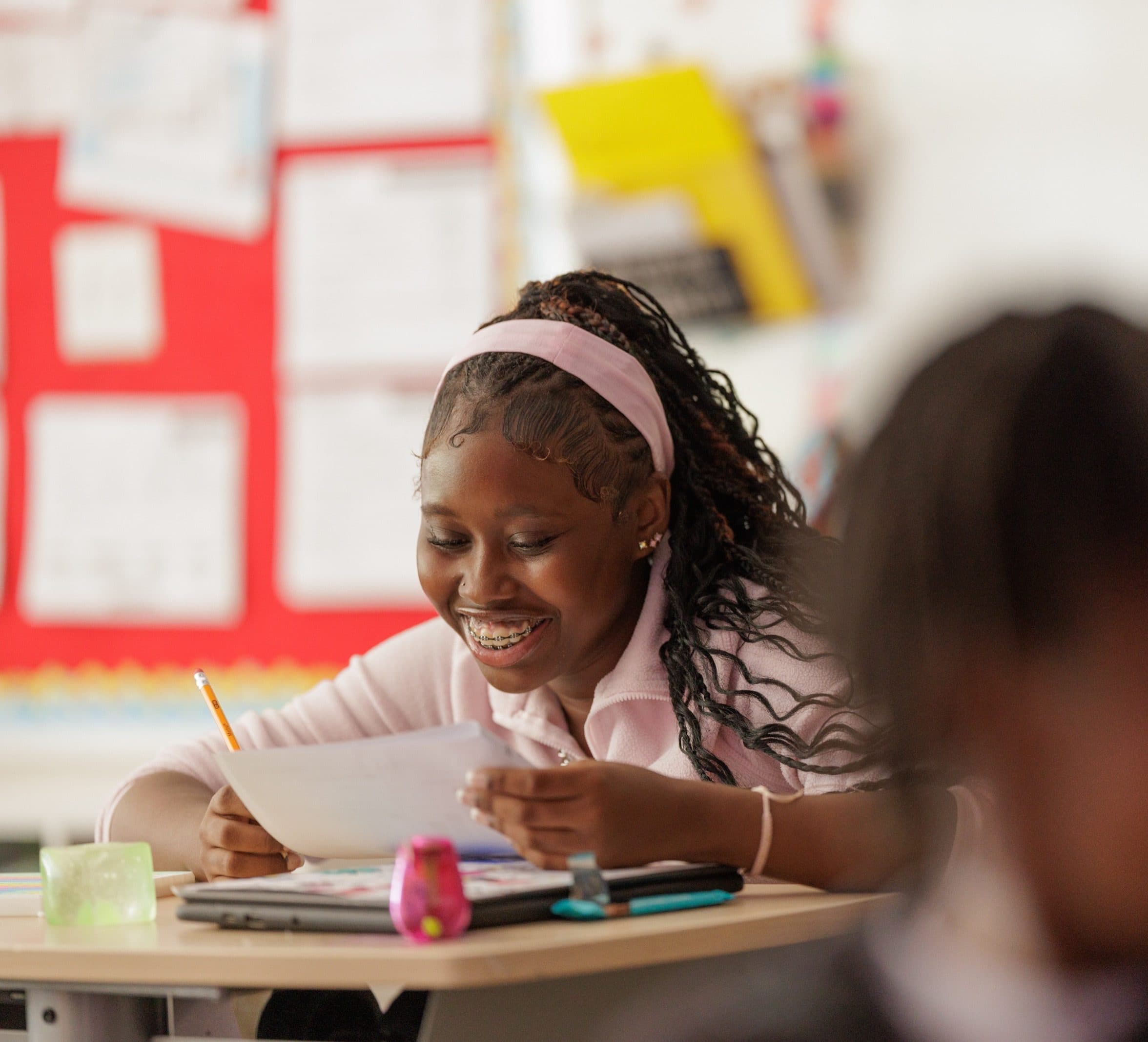 Student smiling while writing at a desk