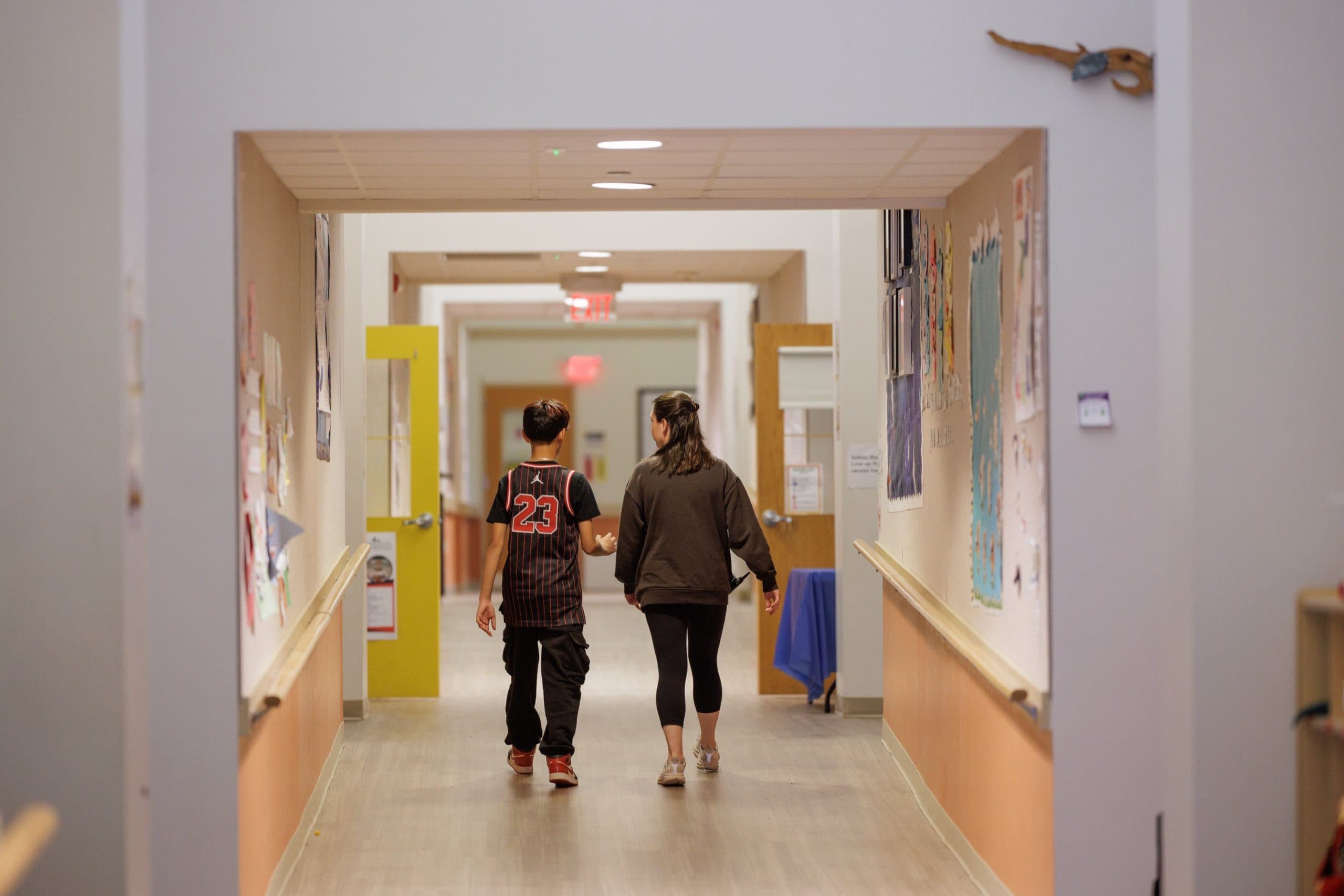 Student walking down the hallway with a teacher