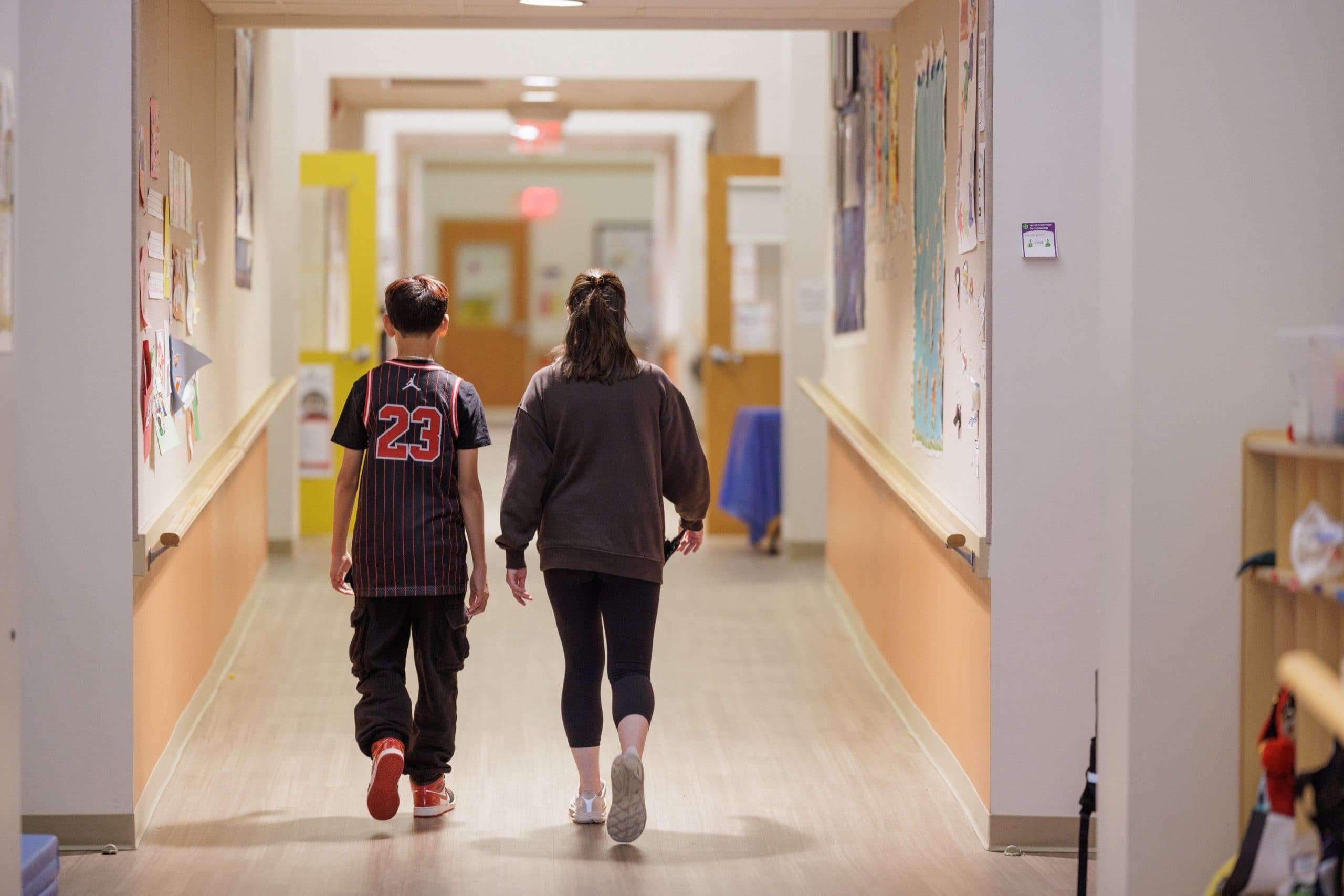 Student walking down the hallway with a teacher