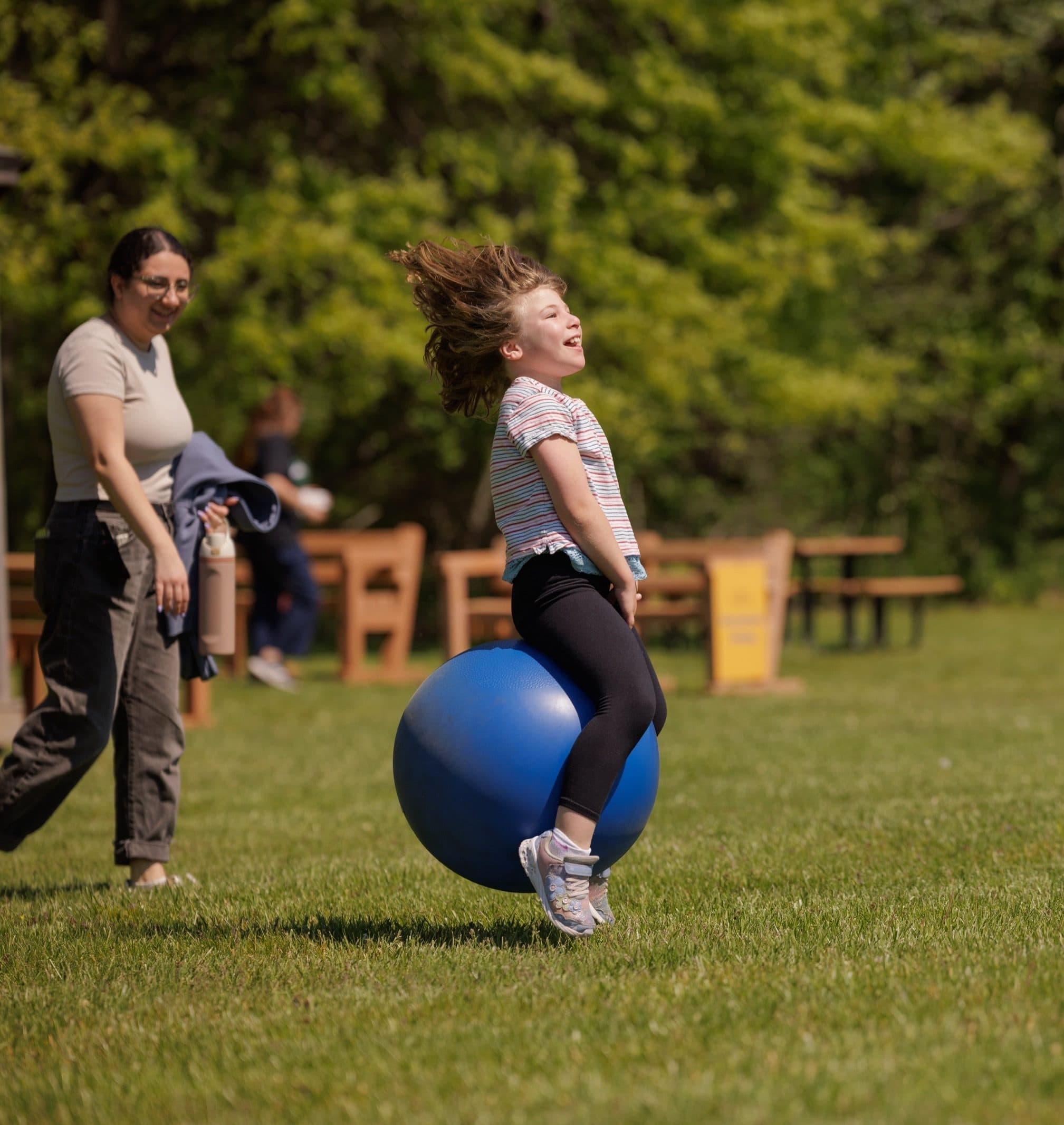 Student bouncing on a ball outdoors