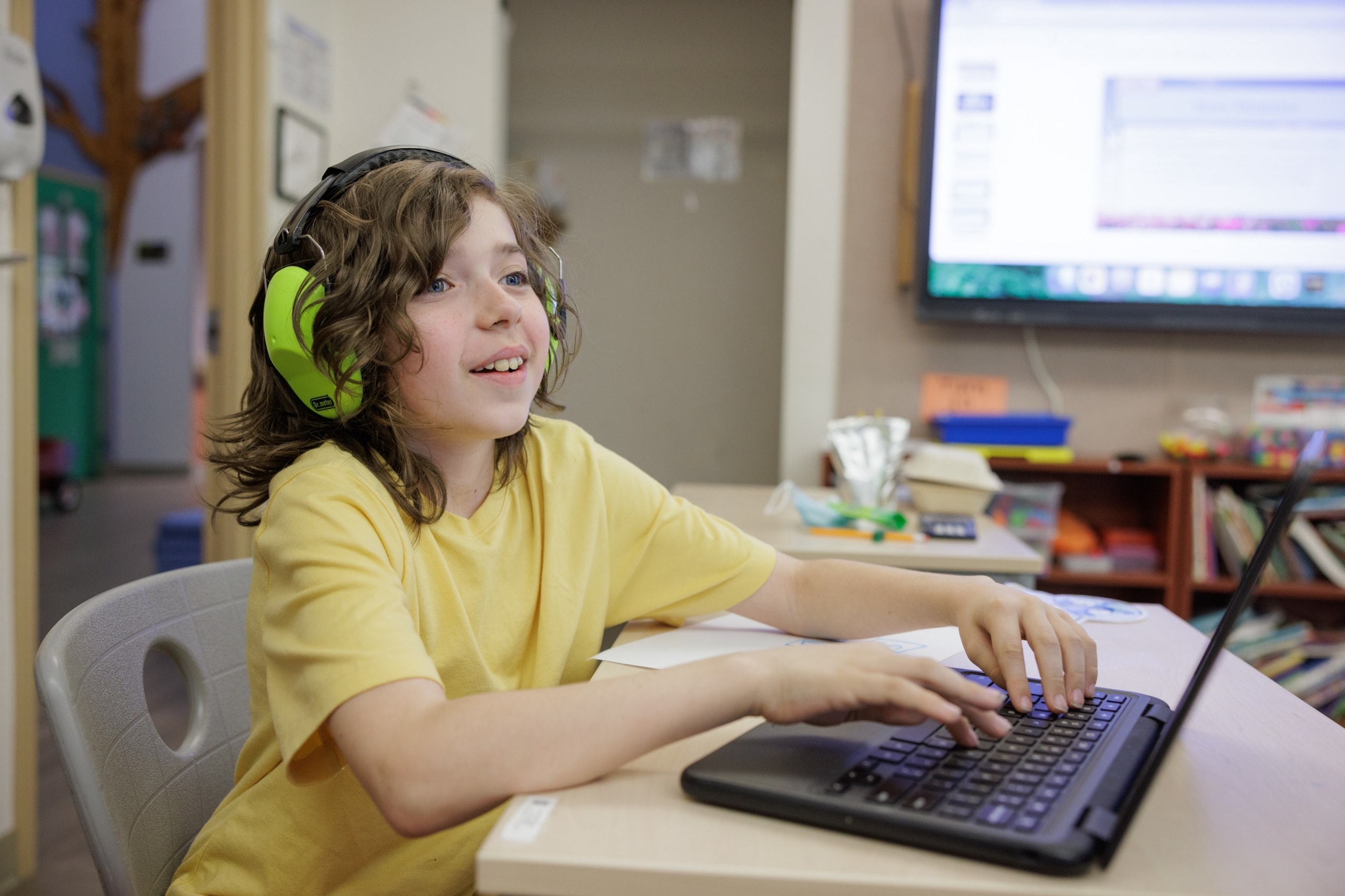 Student wearing noise-reducing ear protection while using a laptop