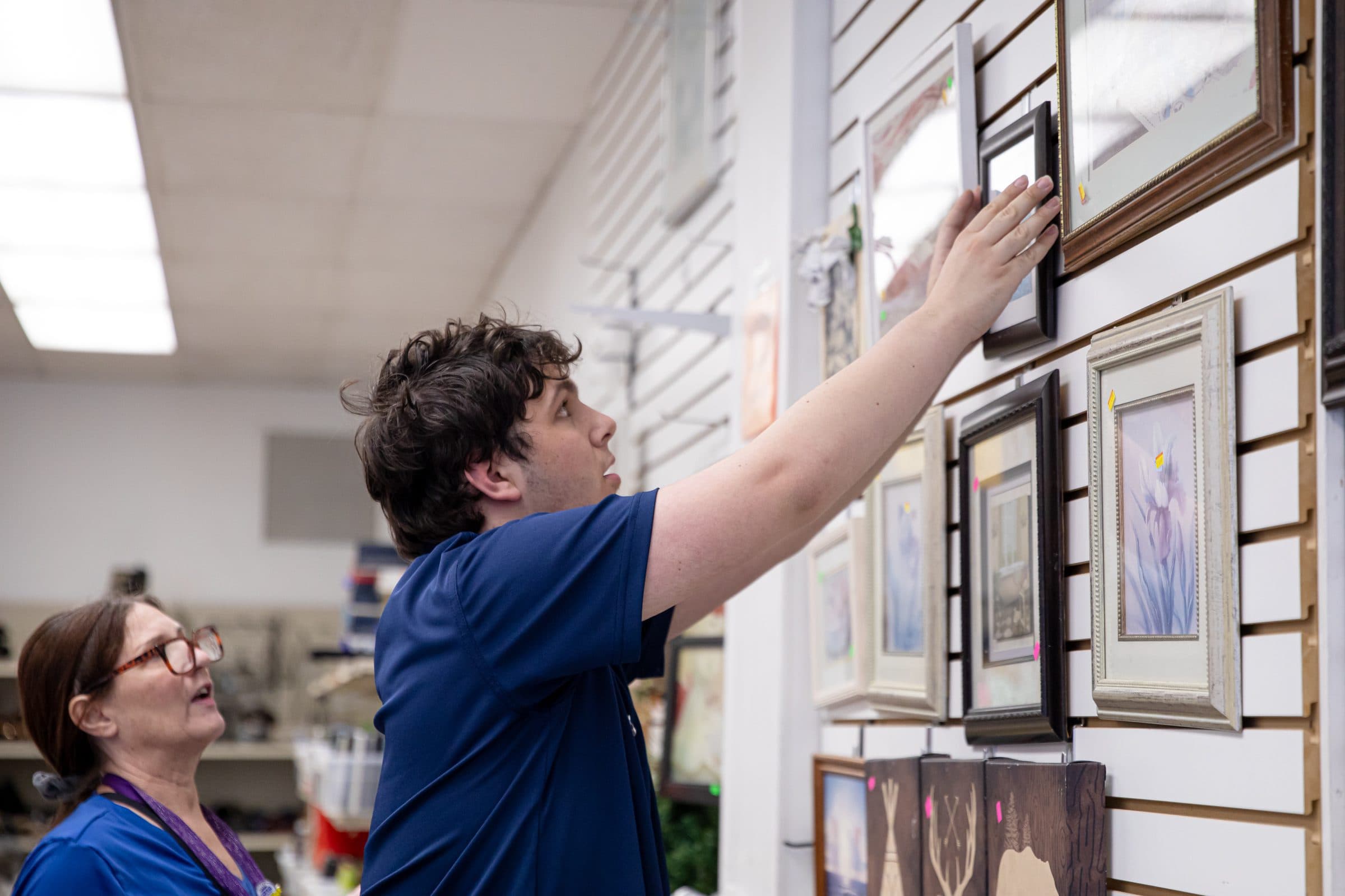 Student reaching to adjust photo frame on the wall
