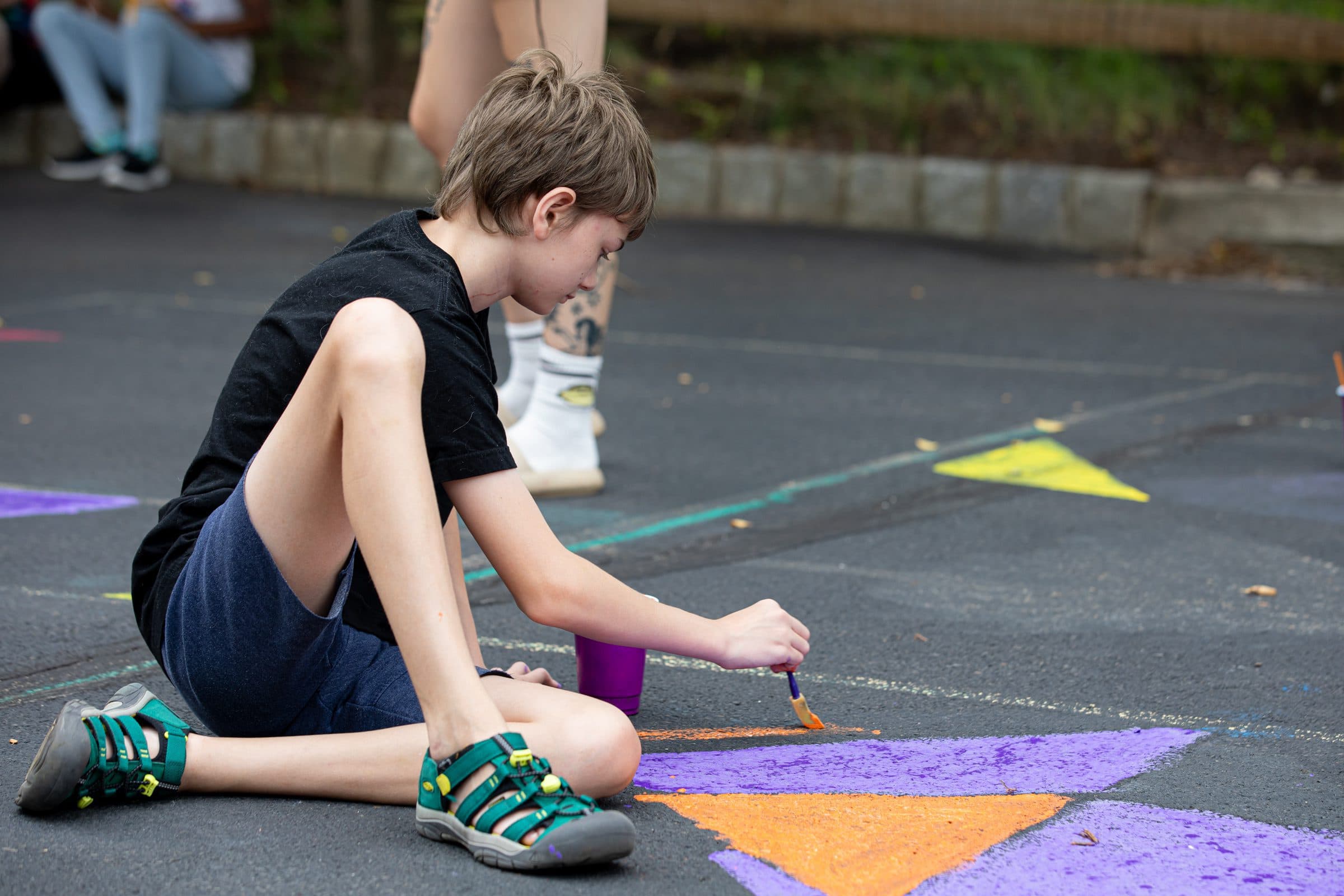 Student painting on the floor outdoors