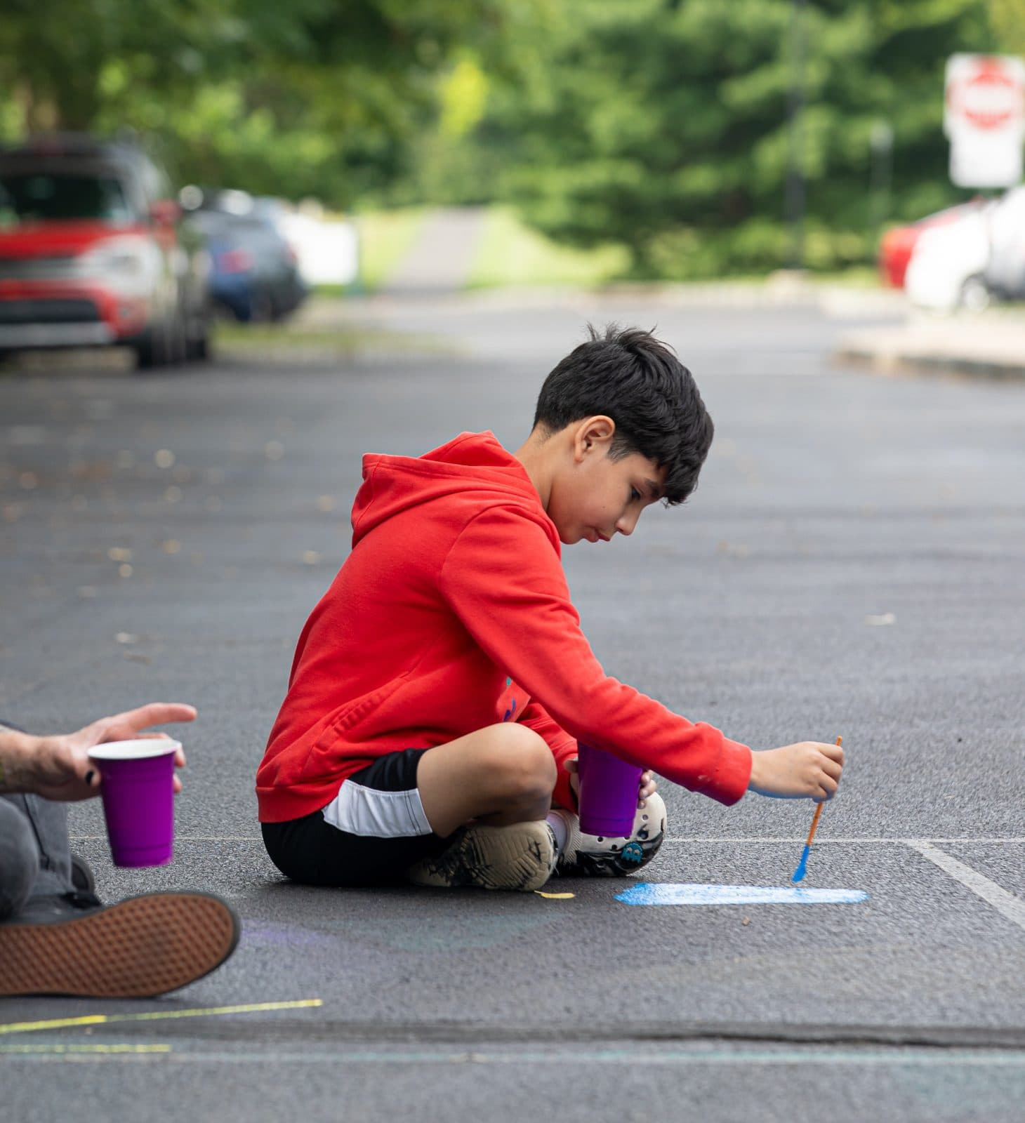 Student painting on the floor outdoors