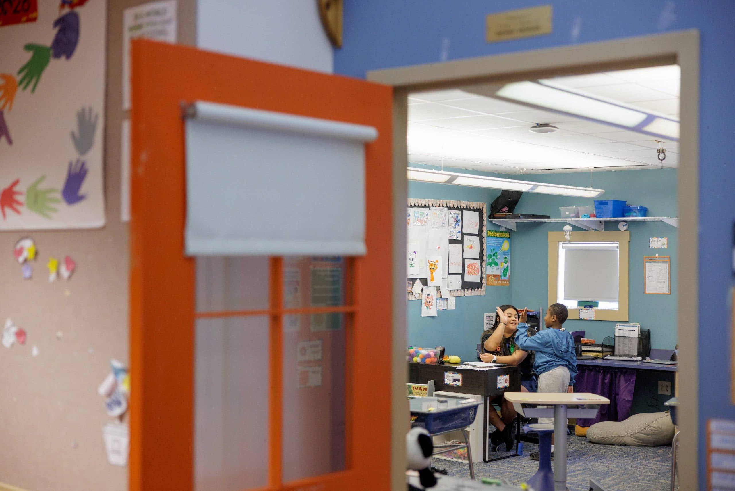 Staff member and student high-fiving in a classroom