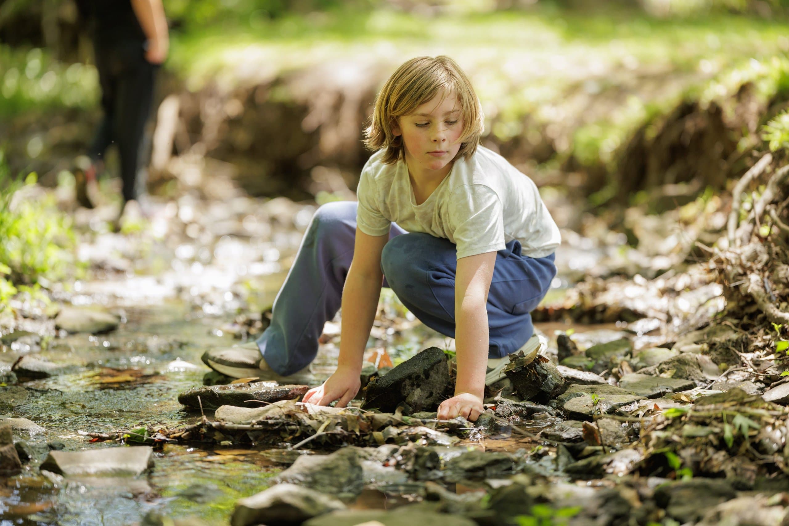 Student examining rocks in a stream