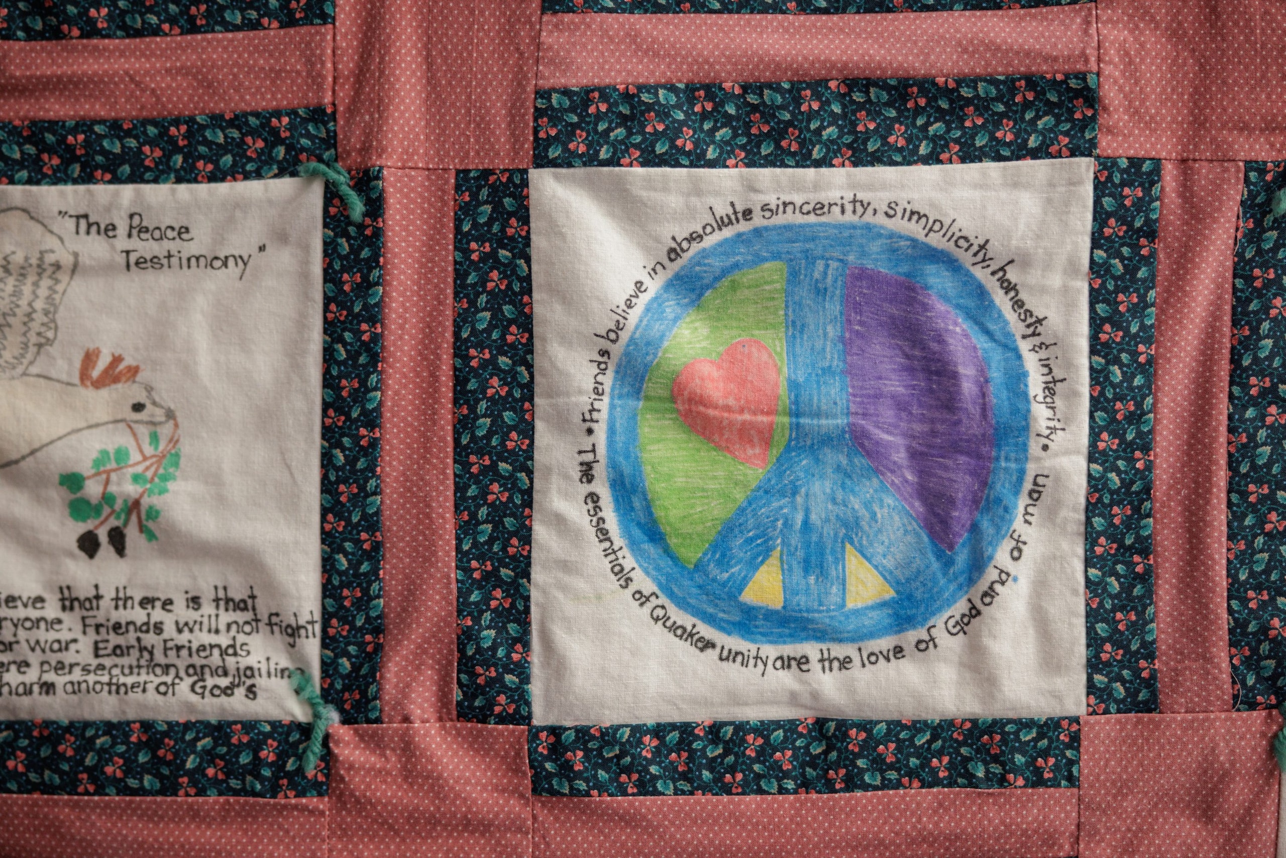 Handmade peace-sign quilt panel displayed at TQS