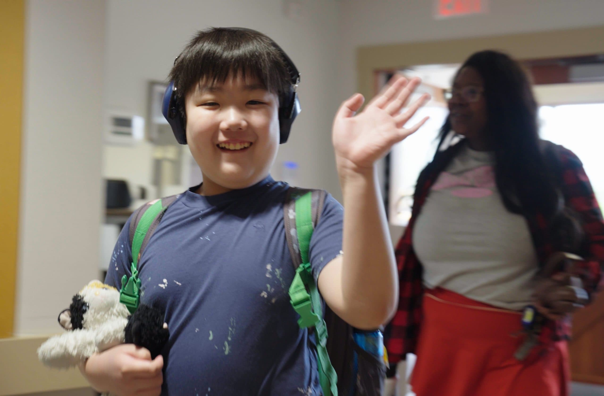 Student wearing headphones, waving