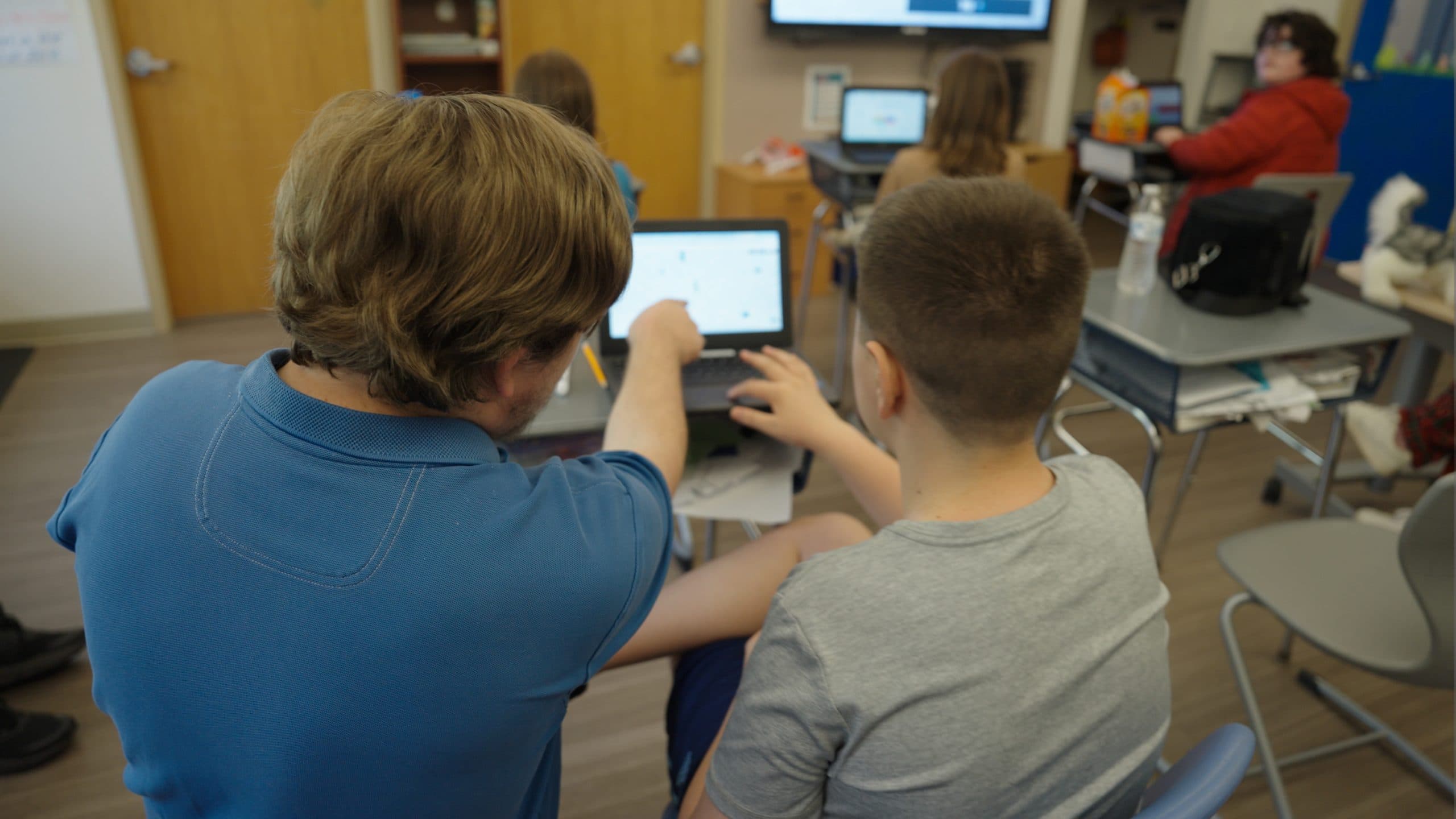 Student and teacher working together on a laptop